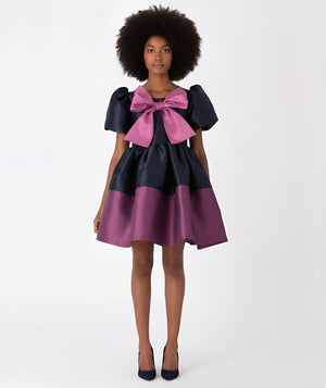 Front view of two-tone purple and navy satin women’s dress with oversized bow – luxury statement occasion dress by Mama Luma.