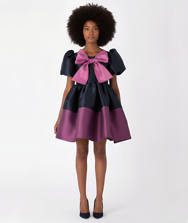 Front view of two-tone purple and navy satin women’s dress with oversized bow – luxury statement occasion dress by Mama Luma.