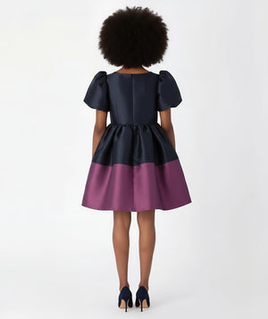Mama Luma’s Purple Bow Special Occasion Women’s Dress featuring a bold navy and plum color-block design. The oversized bow detail and voluminous silhouette bring couture flair to holiday parties, evening events, and family portraits.