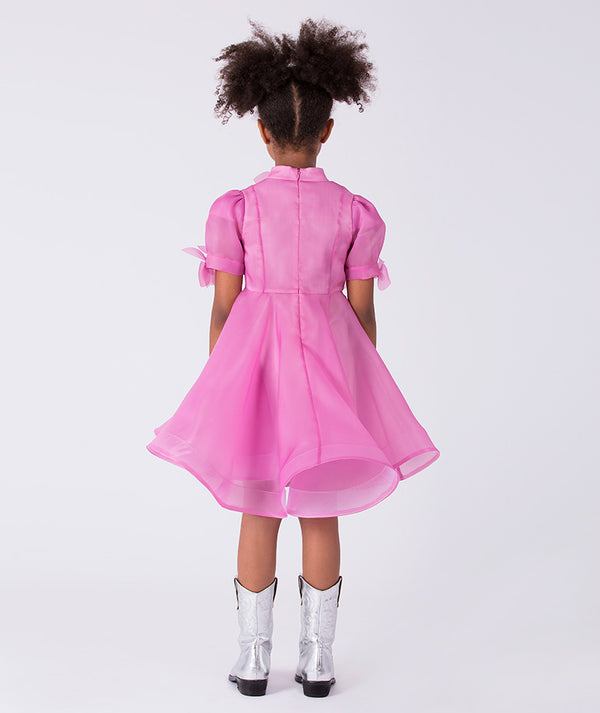 Back view of a sheer organza girls dress featuring a flared silhouette, soft transparency and floral details for refined celebrations