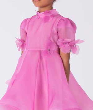 Close-up of three-dimensional organza floral appliqués on a pink girls dress with sheer texture and delicate craftsmanship