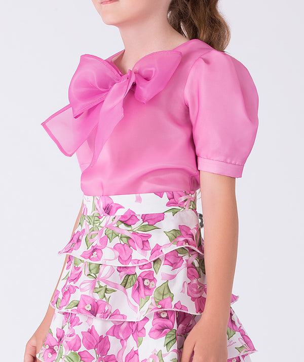 Close-up of sheer puff sleeve top with bow detail on a girls two-piece outfit, highlighting soft structure and refined craftsmanship.