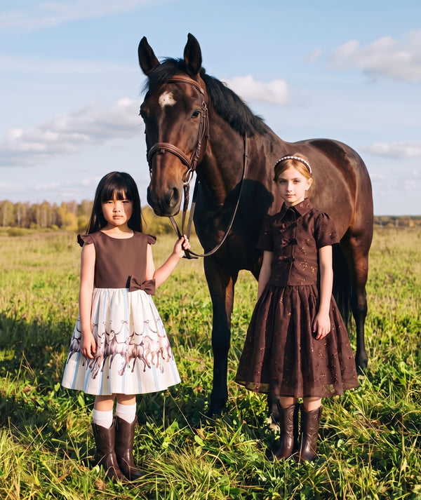 Shimmering mocha girls dress with oversized back bow and metallic bow embellishments from Mama Luma’s Altai Morin Collection.