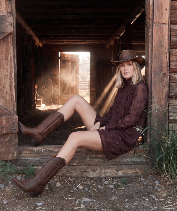 Shimmering Mocha Women's Dress styled with cowboy boots in a Western-inspired editorial setting.