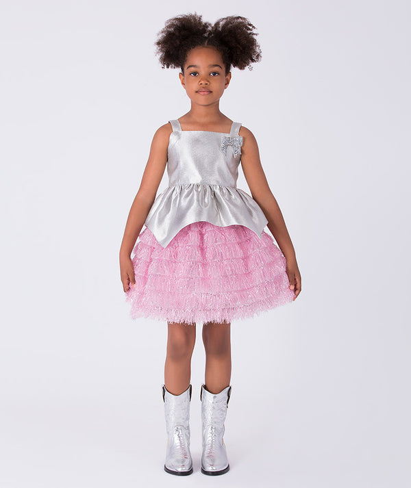 4 years old girl wearing a silver top and pink skirt with white boots on a white background