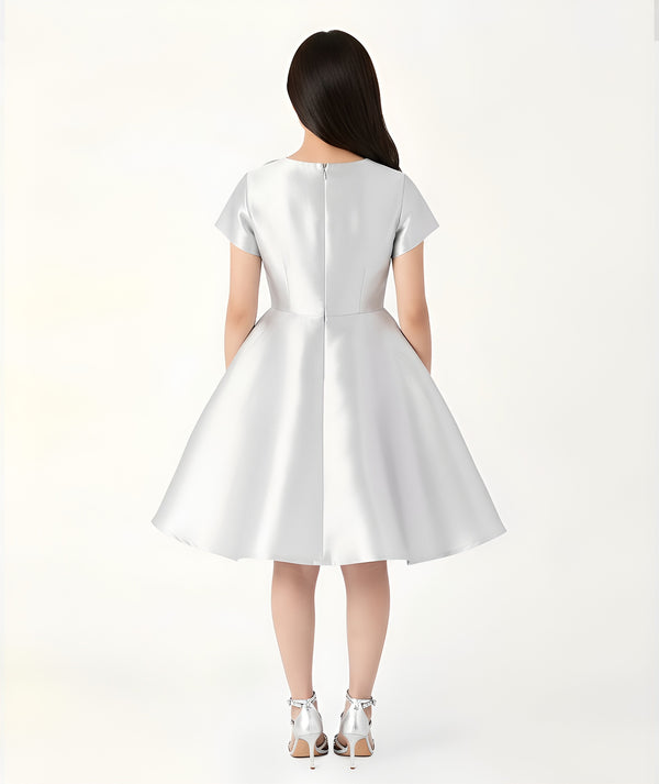 Front view of silver satin women’s dress with oversized sculptural flower on the shoulder – sophisticated evening and event dress by Mama Luma.