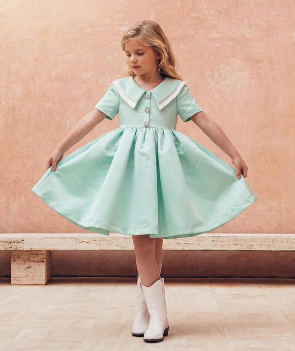 Editorial view of Swan Pearl Mint Girls Dress in mint satin for girls ages 3 to 12, featuring fabric texture and color