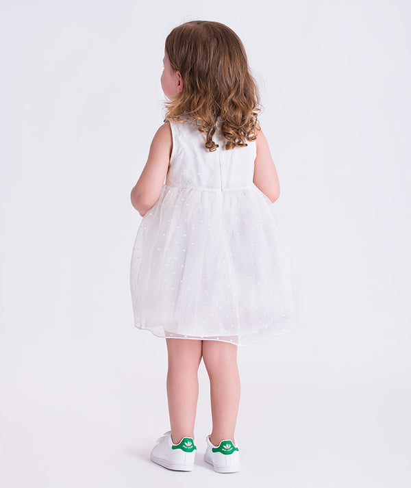 Back view of a swiss dot baby girl dress with lightweight fabric and gentle volume, designed for babies aged 12–36 months.