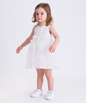 Swiss dot baby girl dress worn by a toddler, featuring a sleeveless design, soft waist bow and airy skirt for special occasions.
