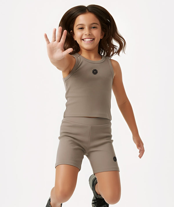 Action lifestyle image of a girl wearing a taupe sleeveless tank top and matching shorts, captured mid-movement for energetic play, active comfort, and everyday athleisure, available in sizes 3–14