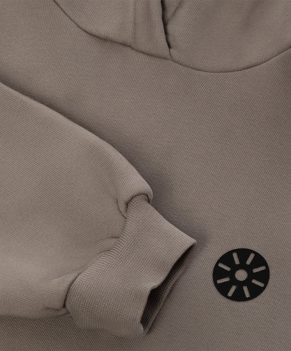 Close-up detail of a taupe girls hoodie highlighting the ribbed sleeve cuff, soft knit texture, and minimalist chest emblem, designed for everyday wear, school outfits, and casual layering, available in sizes 3–14