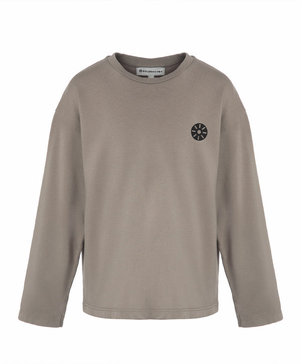 Front view of a taupe girls long sleeve t-shirt with a relaxed fit and minimalist chest emblem, designed for everyday wear, school outfits, and casual layering, available in sizes 3–14