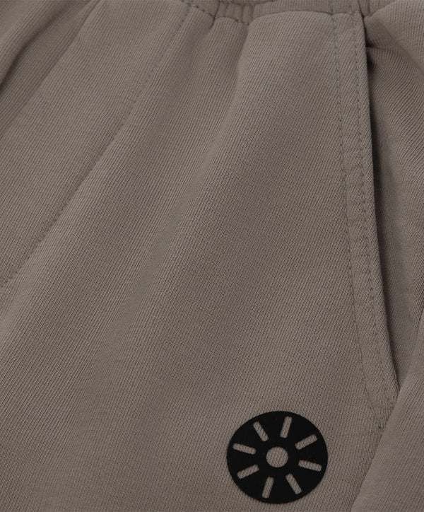 Close-up detail of taupe girls pants highlighting the elastic waistband seam, vertical panel stitching, and minimalist emblem, designed for everyday wear, school outfits, and casual looks, available in sizes 3–14