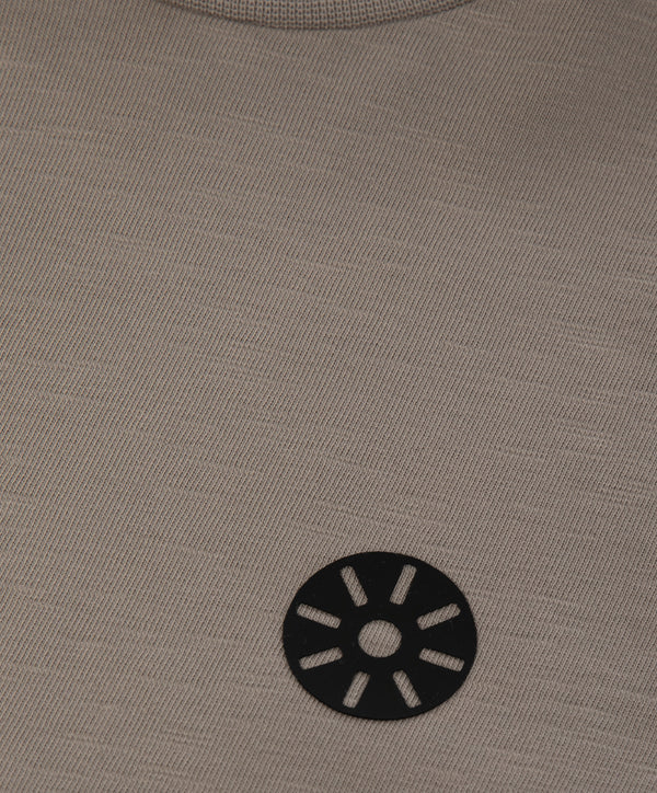 Close-up detail of a taupe short sleeve girls t-shirt featuring a minimalist black chest emblem and soft knit texture, designed for everyday wear, school outfits, and casual looks, available in sizes 3–14