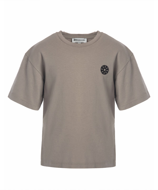 Front view of a taupe short sleeve girls t-shirt with a relaxed fit and minimalist black chest emblem, designed for everyday wear, school outfits, and casual outings, available in sizes 3–14