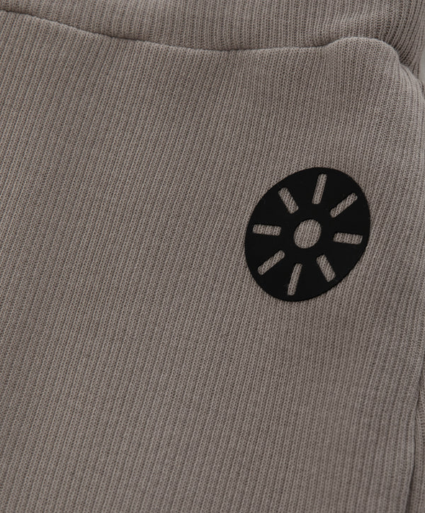 Close-up detail of taupe girls shorts featuring a minimalist black emblem and soft knit texture, designed for everyday wear, school outfits, and casual looks, available in sizes 3–14