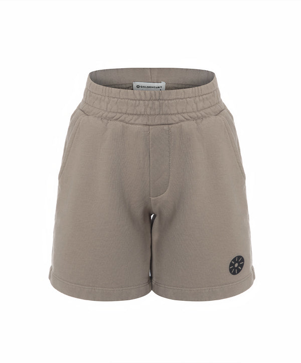 Front view of taupe girls shorts with an elastic waistband and minimalist emblem detail, designed for everyday wear, school outfits, and casual looks, available in sizes 3–14