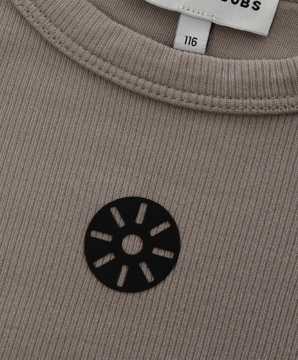 Close-up detail of a taupe girls sleeveless tank top highlighting the ribbed neckline, soft knit texture, and minimalist chest emblem, designed for everyday wear, school outfits, and casual looks, available in sizes 3–14