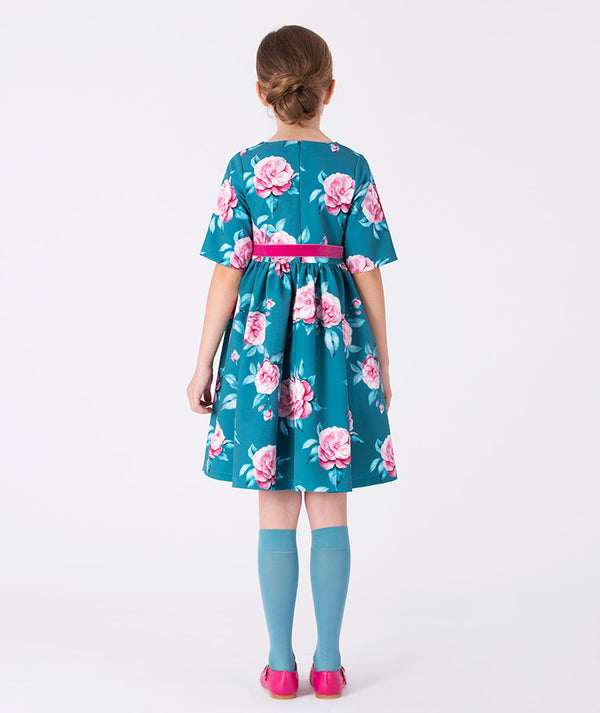 Back view of teal floral dress with pink belt for girls, featuring elegant blooms and soft pleats — ideal for birthdays, weddings, and spring gatherings. Available in sizes 3–12Y