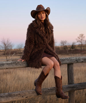 Textured Faux Fur Women's Coat in mocha styled in a ranch setting, featuring plush long-pile texture and a self-tie belt by Mama Luma.