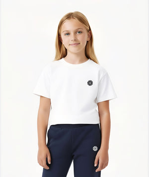Front-facing lifestyle image of a girl wearing a white short sleeve t-shirt with navy pants, styled for clean everyday outfits, school-ready comfort, and simple athleisure looks, available in sizes 3–14