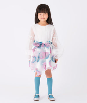 Girl wearing a white organza blouse with voluminous sleeves and a pastel feathered skirt (3–12Y) accented with a pink and blue bow — perfect for weddings, birthdays, and elegant celebrations