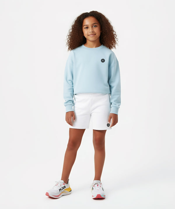 Girl wearing a light blue sweatshirt and white shorts, styled for everyday athleisure, school days, and active play, available in sizes 3–14