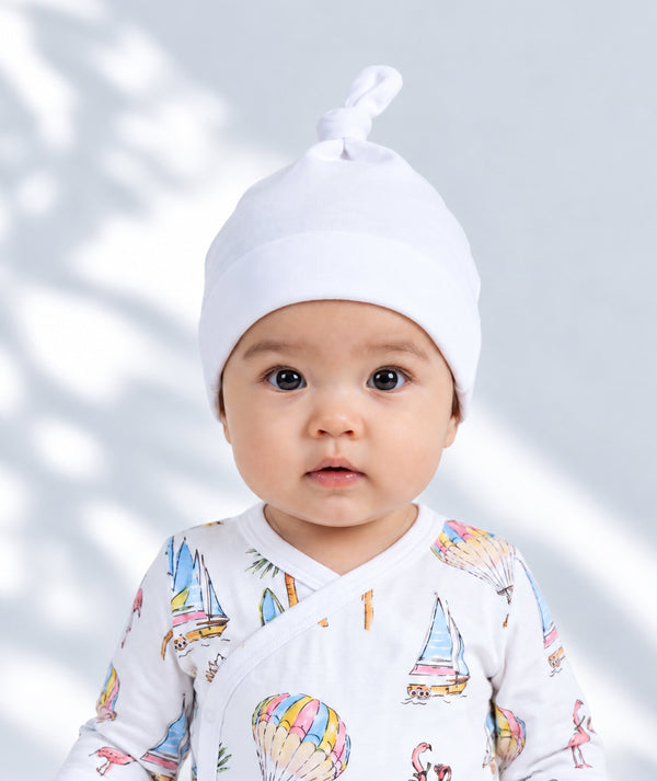 White baby clothing and accessories in a soft studio photograph, alternate view.