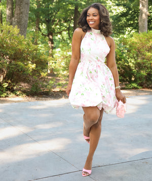 Woman wearing a white floral summer dress in a garden