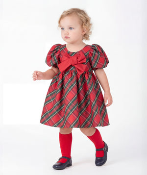 Front view of Mama Luma Balloon Sleeve Tartan Baby Girl Dress featuring red and green plaid, puff sleeves, and a statement crimson bow.