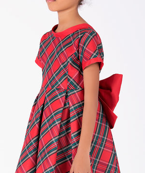 Close-up of the Tartan Bow Girls Dress by Mama Luma, highlighting diagonal tartan checks, contrasting red sleeve cuffs, and the oversized bow detail.